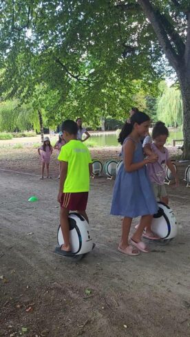 Éco Activité de Camping Groupe d'enfants découvrant la gyroroue solaire HelioEvents dans un camping