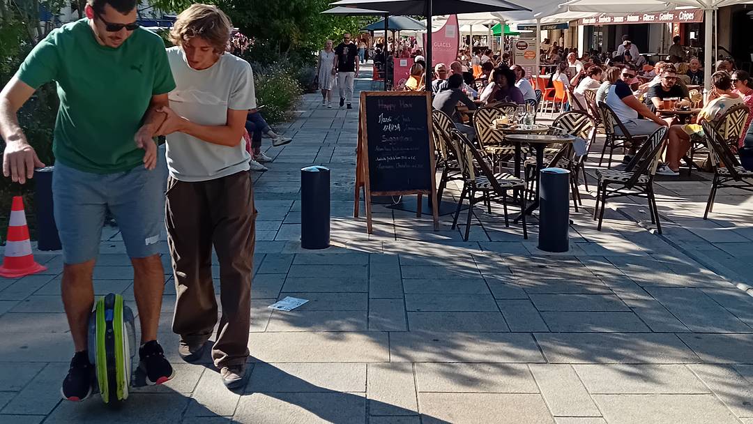 Moniteur HelioEvents accompagnant un jeune sur une gyroroue solaire sur une place piétonne de centre-ville